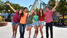 teens standing in front of a roller coaster
