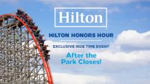 coaster train going down drop hill with rides hands up