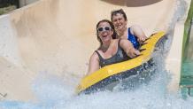 Two women ride a slide at Hurricane Harbor