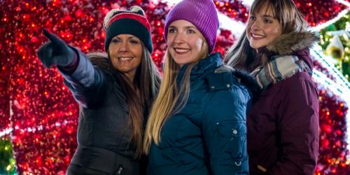 three women looking at holiday lights standing in front of a large holiday tree